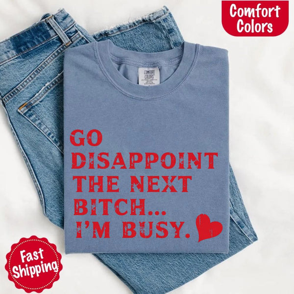 May include bold red distressed typography with the phrase “Go Disappoint The Next Bitch… I’m Busy.” alongside a red heart, expressing sass, confidence, and attitude.