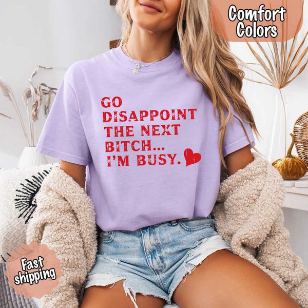 May include bold red distressed typography with the phrase “Go Disappoint The Next Bitch… I’m Busy.” alongside a red heart, expressing sass, confidence, and attitude.