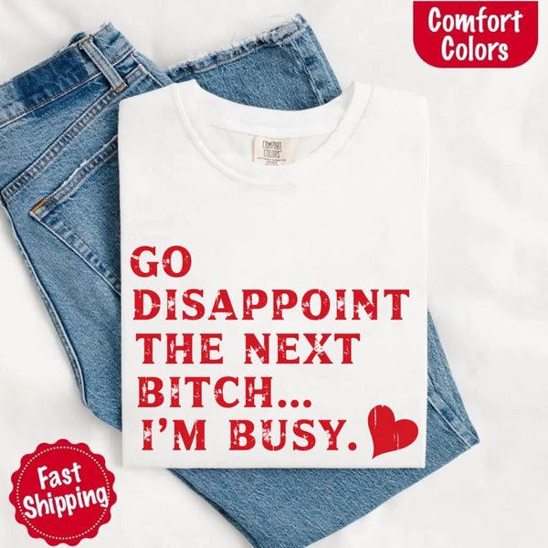 May include bold red distressed typography with the phrase “Go Disappoint The Next Bitch… I’m Busy.” alongside a red heart, expressing sass, confidence, and attitude.