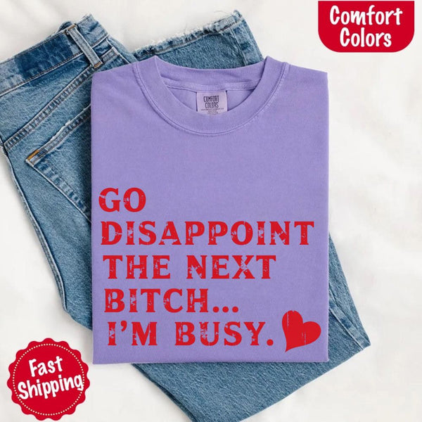 May include bold red distressed typography with the phrase “Go Disappoint The Next Bitch… I’m Busy.” alongside a red heart, expressing sass, confidence, and attitude.