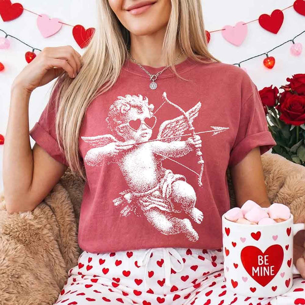 May include a Comfort Colors unisex T-shirt with a halftone pixel art Cupid Valentine’s Day graphic.