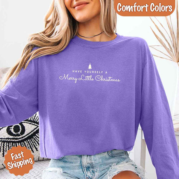 May include a Comfort Colors long sleeve shirt featuring the phrase “Have Yourself a Merry Christmas” in festive print, displayed flat with soft cotton texture and seasonal tones.
