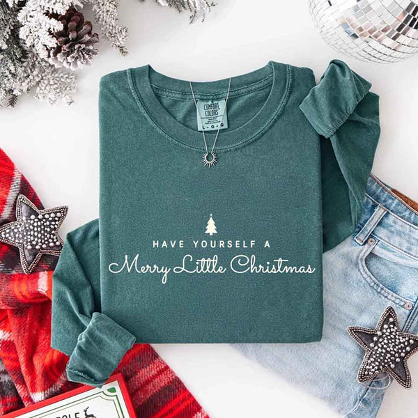May include a Comfort Colors long sleeve shirt featuring the phrase “Have Yourself a Merry Christmas” in festive print, displayed flat with soft cotton texture and seasonal tones.