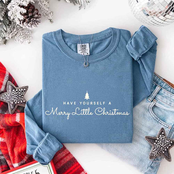 May include a Comfort Colors long sleeve shirt featuring the phrase “Have Yourself a Merry Christmas” in festive print, displayed flat with soft cotton texture and seasonal tones.