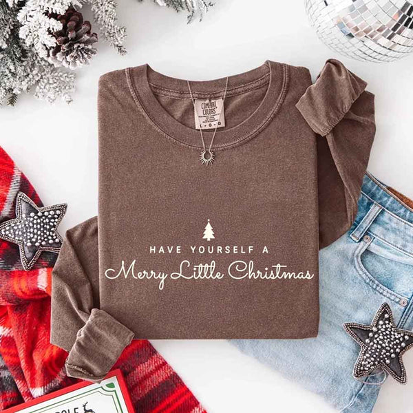 May include a Comfort Colors long sleeve shirt featuring the phrase “Have Yourself a Merry Christmas” in festive print, displayed flat with soft cotton texture and seasonal tones.