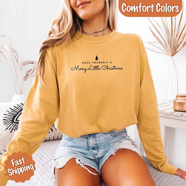 May include a Comfort Colors long sleeve shirt featuring the phrase “Have Yourself a Merry Christmas” in festive print, displayed flat with soft cotton texture and seasonal tones.