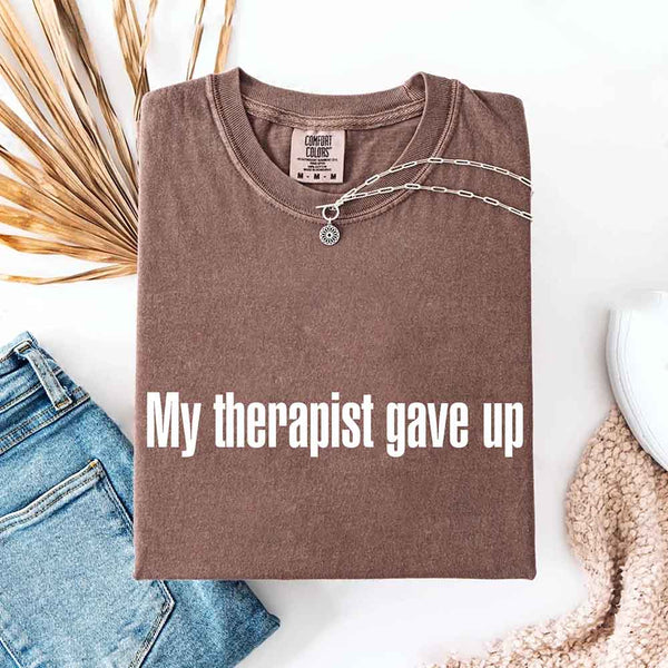 May include a Comfort Colors short-sleeve shirt with the printed phrase My Therapist Gave Up in a simple, bold design.