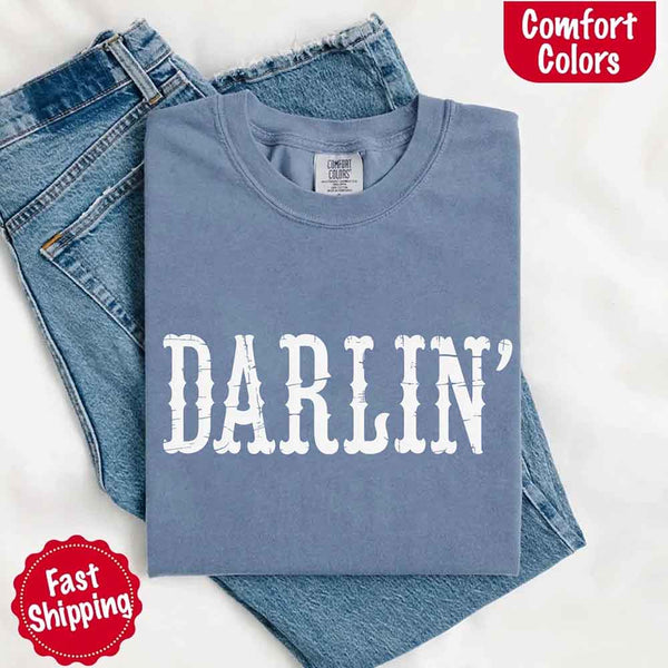 May include bold black distressed Western-style typography featuring the word “Darlin’,” evoking country charm with a vintage, rustic feel.