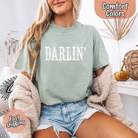 May include bold black distressed Western-style typography featuring the word “Darlin’,” evoking country charm with a vintage, rustic feel.