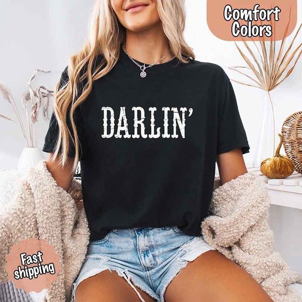 May include bold black distressed Western-style typography featuring the word “Darlin’,” evoking country charm with a vintage, rustic feel.