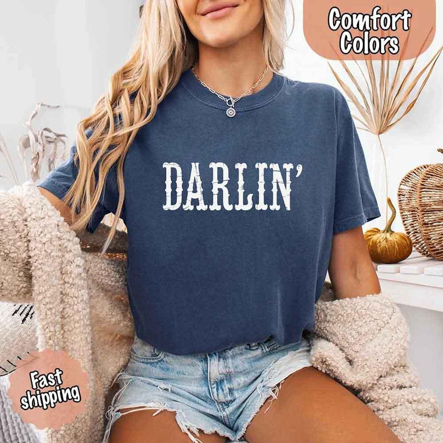 May include bold black distressed Western-style typography featuring the word “Darlin’,” evoking country charm with a vintage, rustic feel.
