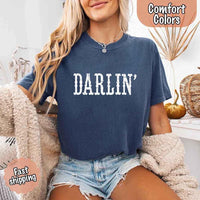 May include bold black distressed Western-style typography featuring the word “Darlin’,” evoking country charm with a vintage, rustic feel.