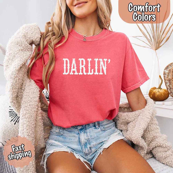 May include bold black distressed Western-style typography featuring the word “Darlin’,” evoking country charm with a vintage, rustic feel.