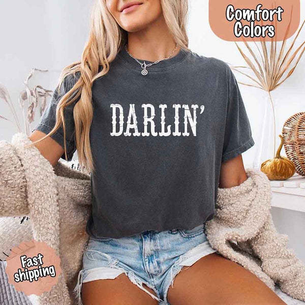 May include bold black distressed Western-style typography featuring the word “Darlin’,” evoking country charm with a vintage, rustic feel.