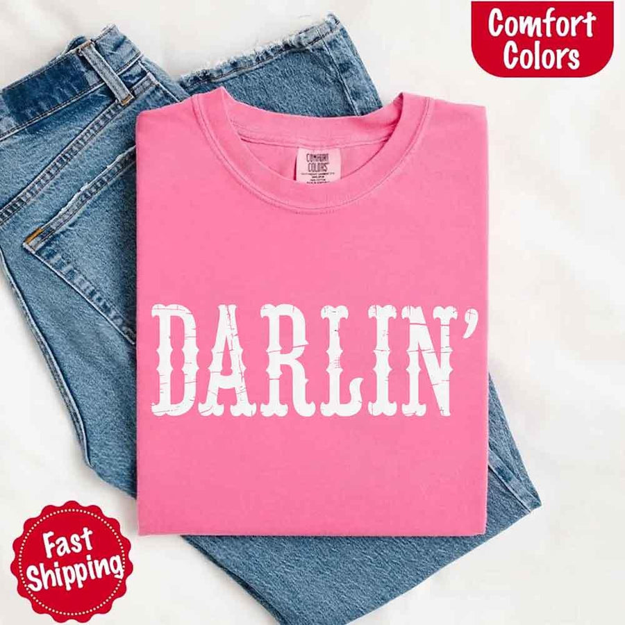 May include bold black distressed Western-style typography featuring the word “Darlin’,” evoking country charm with a vintage, rustic feel.