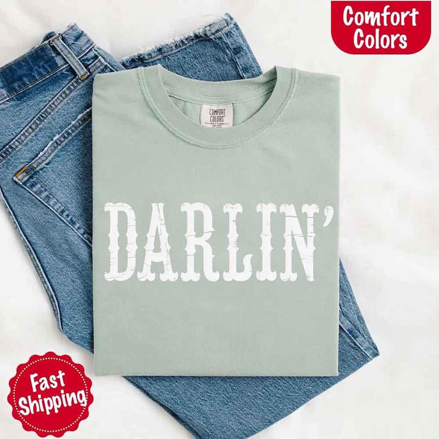 May include bold black distressed Western-style typography featuring the word “Darlin’,” evoking country charm with a vintage, rustic feel.