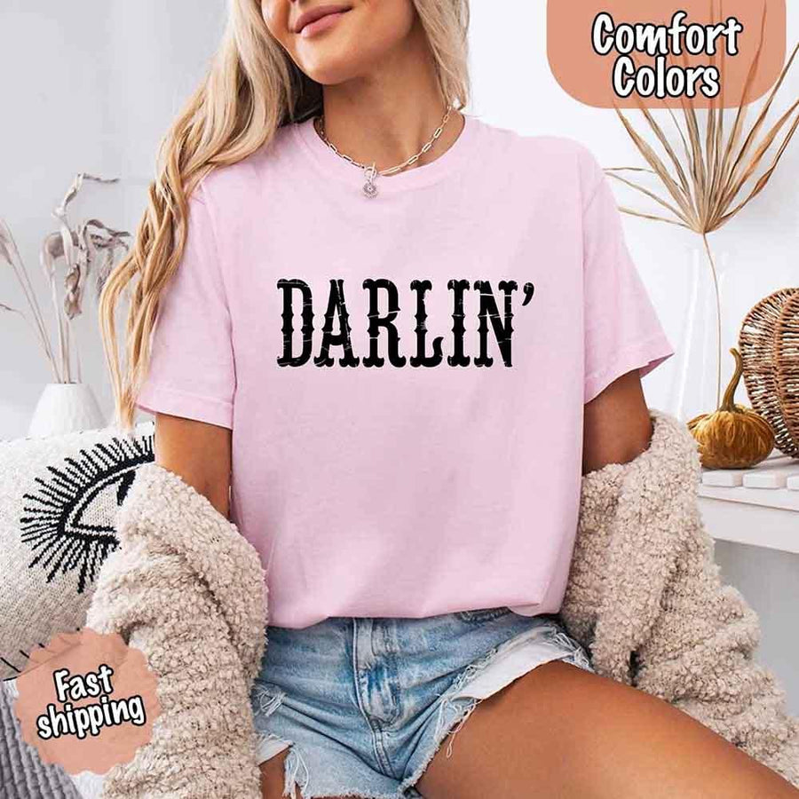 May include bold black distressed Western-style typography featuring the word “Darlin’,” evoking country charm with a vintage, rustic feel.