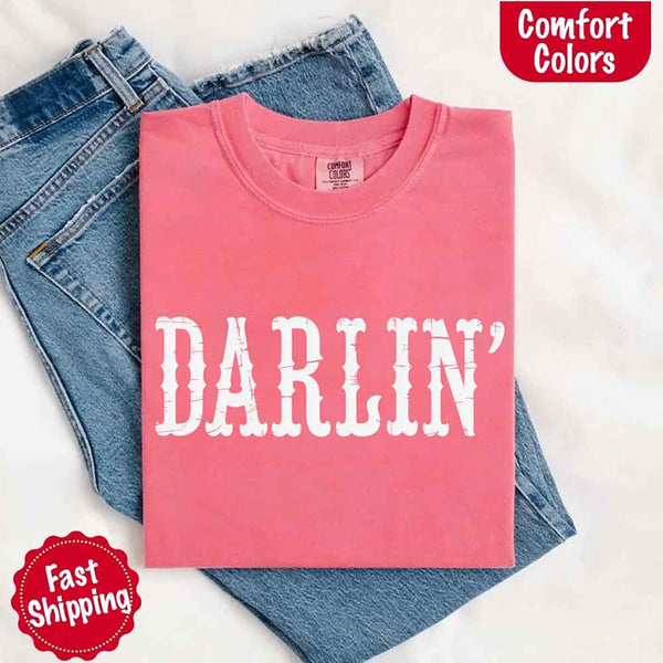 May include bold black distressed Western-style typography featuring the word “Darlin’,” evoking country charm with a vintage, rustic feel.
