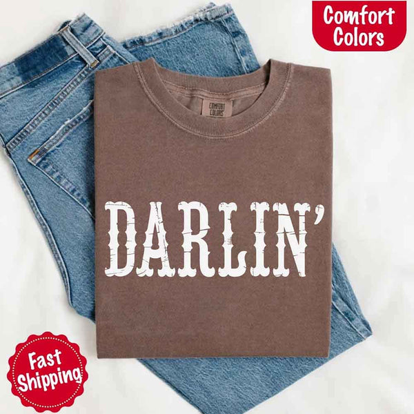 May include bold black distressed Western-style typography featuring the word “Darlin’,” evoking country charm with a vintage, rustic feel.