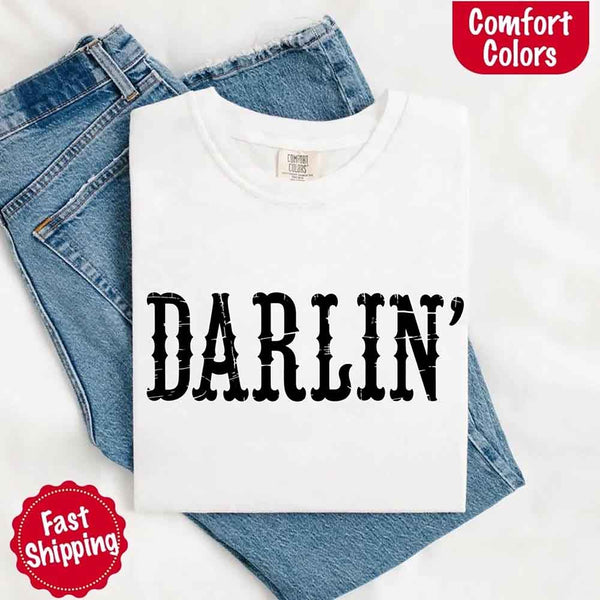 May include bold black distressed Western-style typography featuring the word “Darlin’,” evoking country charm with a vintage, rustic feel.