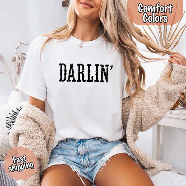 May include bold black distressed Western-style typography featuring the word “Darlin’,” evoking country charm with a vintage, rustic feel.