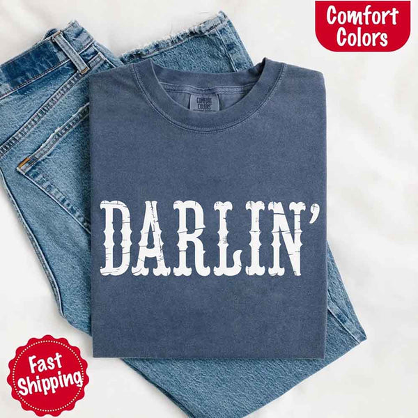 May include bold black distressed Western-style typography featuring the word “Darlin’,” evoking country charm with a vintage, rustic feel.