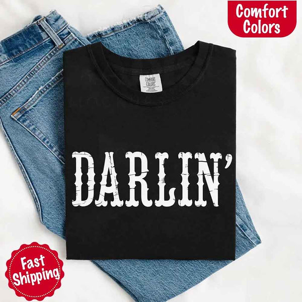 May include bold black distressed Western-style typography featuring the word “Darlin’,” evoking country charm with a vintage, rustic feel.