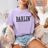 May include bold black distressed Western-style typography featuring the word “Darlin’,” evoking country charm with a vintage, rustic feel.