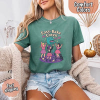 May include Easy Bake Coven graphic with three witch girls baking pies, retro oven, skulls, gravestone, and black cat – vintage 90s Halloween shirt.