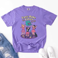 May include Easy Bake Coven graphic with three witch girls baking pies, retro oven, skulls, gravestone, and black cat – vintage 90s Halloween shirt.