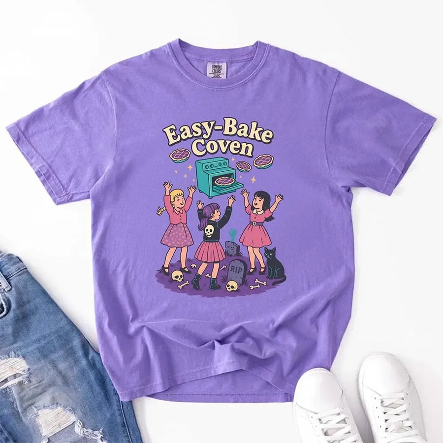 May include Easy Bake Coven graphic with three witch girls baking pies, retro oven, skulls, gravestone, and black cat – vintage 90s Halloween shirt.