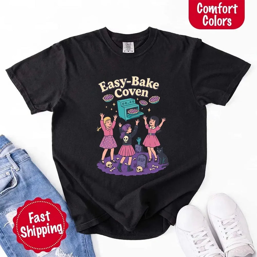 May include Easy Bake Coven graphic with three witch girls baking pies, retro oven, skulls, gravestone, and black cat – vintage 90s Halloween shirt.
