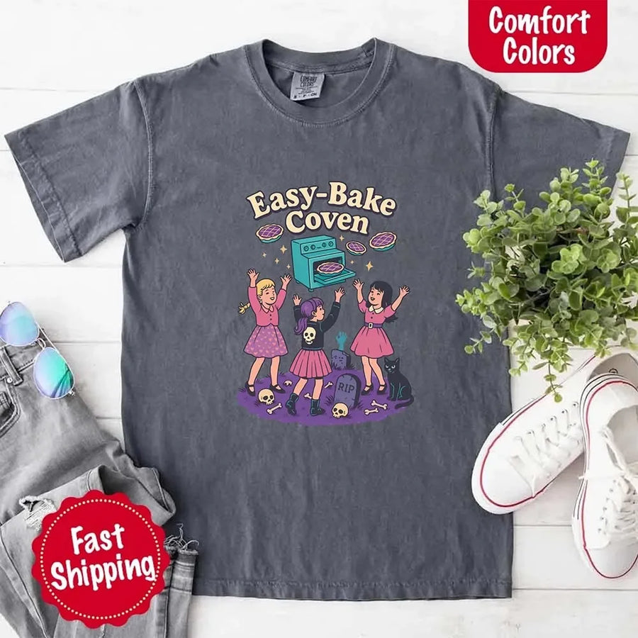 May include Easy Bake Coven graphic with three witch girls baking pies, retro oven, skulls, gravestone, and black cat – vintage 90s Halloween shirt.