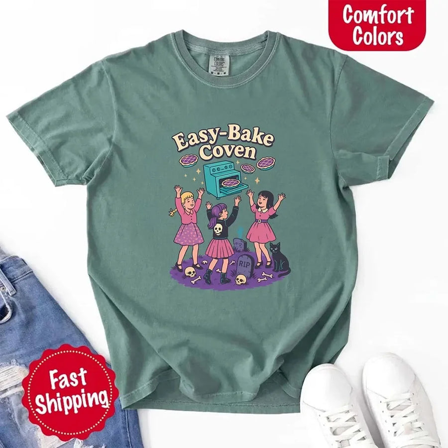 May include Easy Bake Coven graphic with three witch girls baking pies, retro oven, skulls, gravestone, and black cat – vintage 90s Halloween shirt.