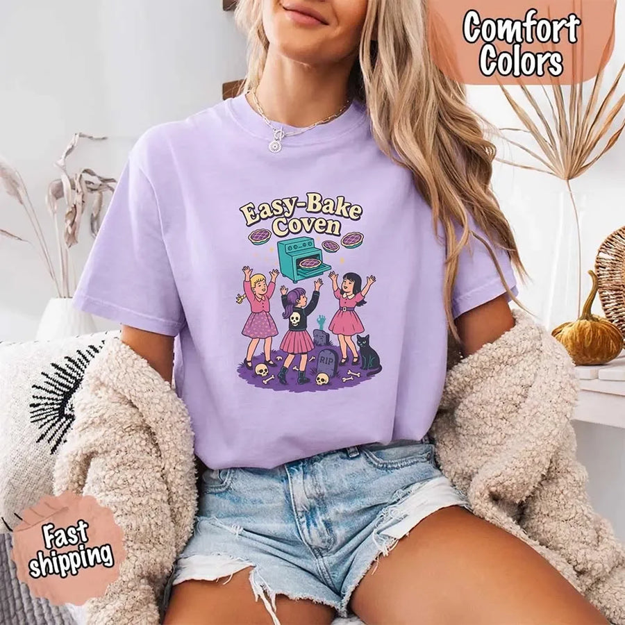 May include Easy Bake Coven graphic with three witch girls baking pies, retro oven, skulls, gravestone, and black cat – vintage 90s Halloween shirt.