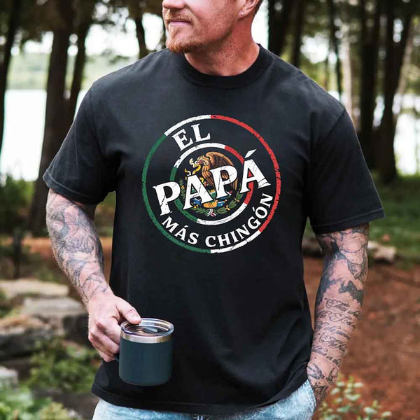 May include bold distressed text that reads “El Papá Más Chingón” over a circular Mexican flag-inspired design with an eagle emblem, celebrating proud and confident fatherhood with cultural pride.
