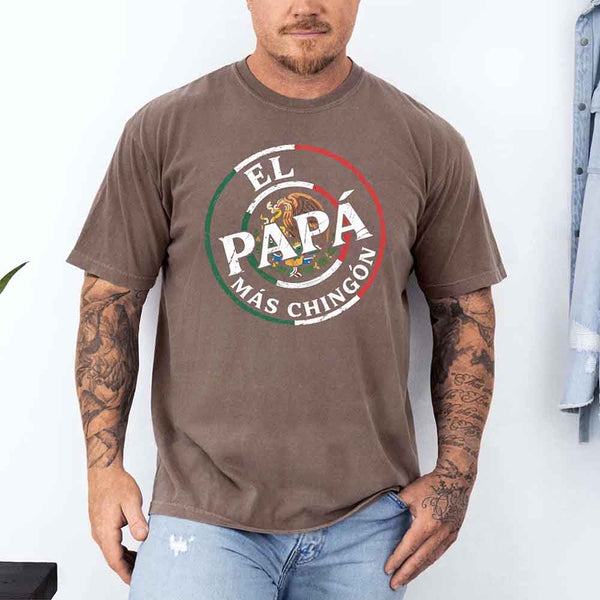 May include bold distressed text that reads “El Papá Más Chingón” over a circular Mexican flag-inspired design with an eagle emblem, celebrating proud and confident fatherhood with cultural pride.