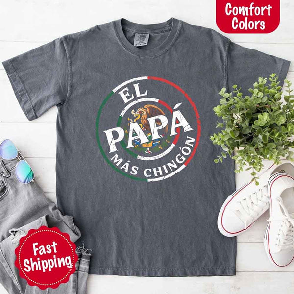 May include bold distressed text that reads “El Papá Más Chingón” over a circular Mexican flag-inspired design with an eagle emblem, celebrating proud and confident fatherhood with cultural pride.