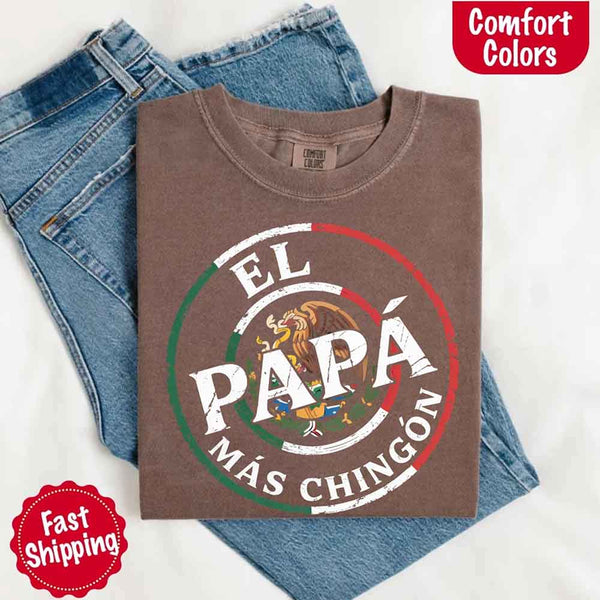 May include bold distressed text that reads “El Papá Más Chingón” over a circular Mexican flag-inspired design with an eagle emblem, celebrating proud and confident fatherhood with cultural pride.