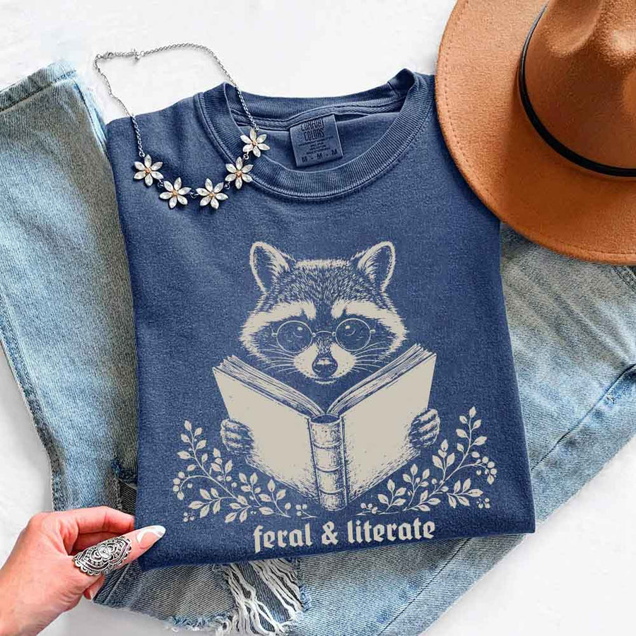 May include Feral & Literate Raccoon Comfort Colors t-shirt with funny book lover graphic, relaxed unisex fit, and garment-dyed cotton