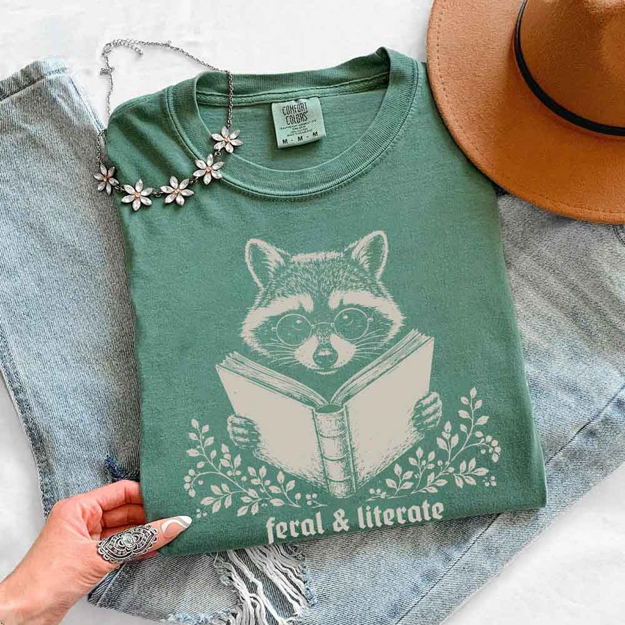 May include Feral & Literate Raccoon Comfort Colors t-shirt with funny book lover graphic, relaxed unisex fit, and garment-dyed cotton