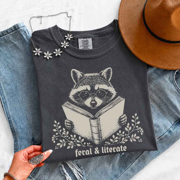 May include Feral & Literate Raccoon Comfort Colors t-shirt with funny book lover graphic, relaxed unisex fit, and garment-dyed cotton