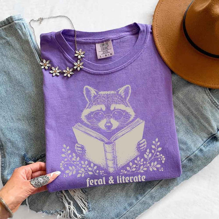 May include Feral & Literate Raccoon Comfort Colors t-shirt with funny book lover graphic, relaxed unisex fit, and garment-dyed cotton