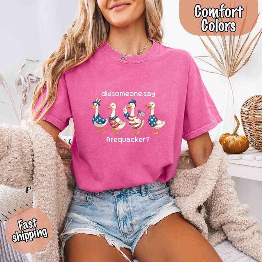 Person wearing a pink t-shirt with a graphic and text, sitting on a couch.