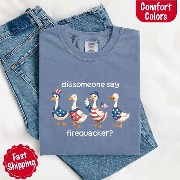 Blue t-shirt with graphic of ducks wearing American flags and text 'did someone say firequacker?' on a white background.
