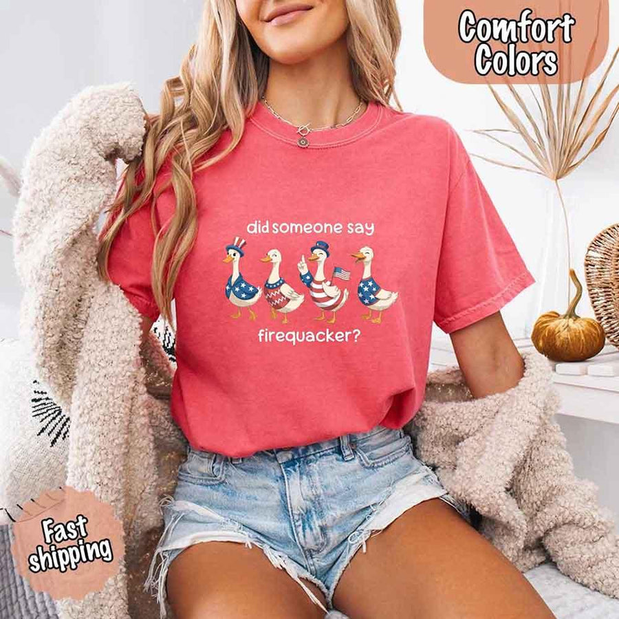 Person wearing a pink t-shirt with a graphic and text, sitting indoors.