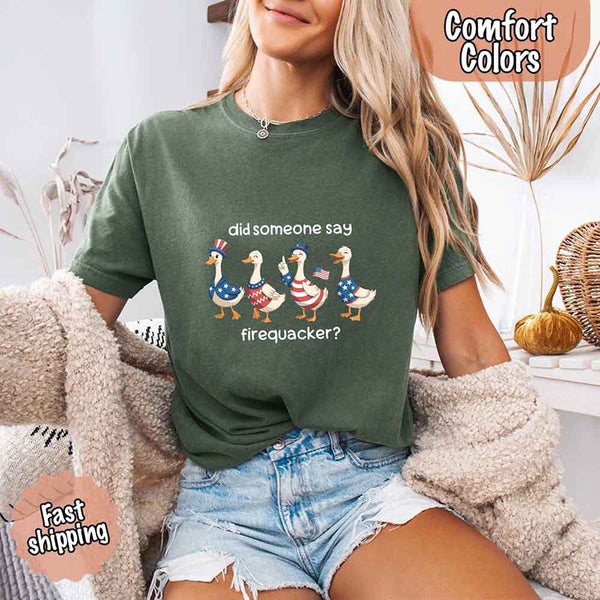 Person wearing a green t-shirt with a graphic of ducks and text, sitting on a couch.