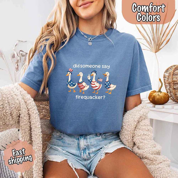 Person wearing a blue t-shirt with a graphic of ducks and text, sitting on a couch.