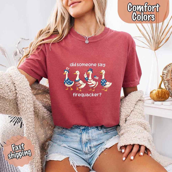 Person wearing a red t-shirt with a graphic of ducks and text, sitting indoors.