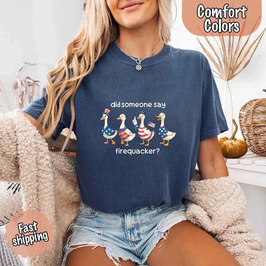 Person wearing a navy blue t-shirt with a graphic and text, sitting on a couch.